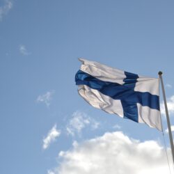 Suomen lippu sinitaivasta vasten.