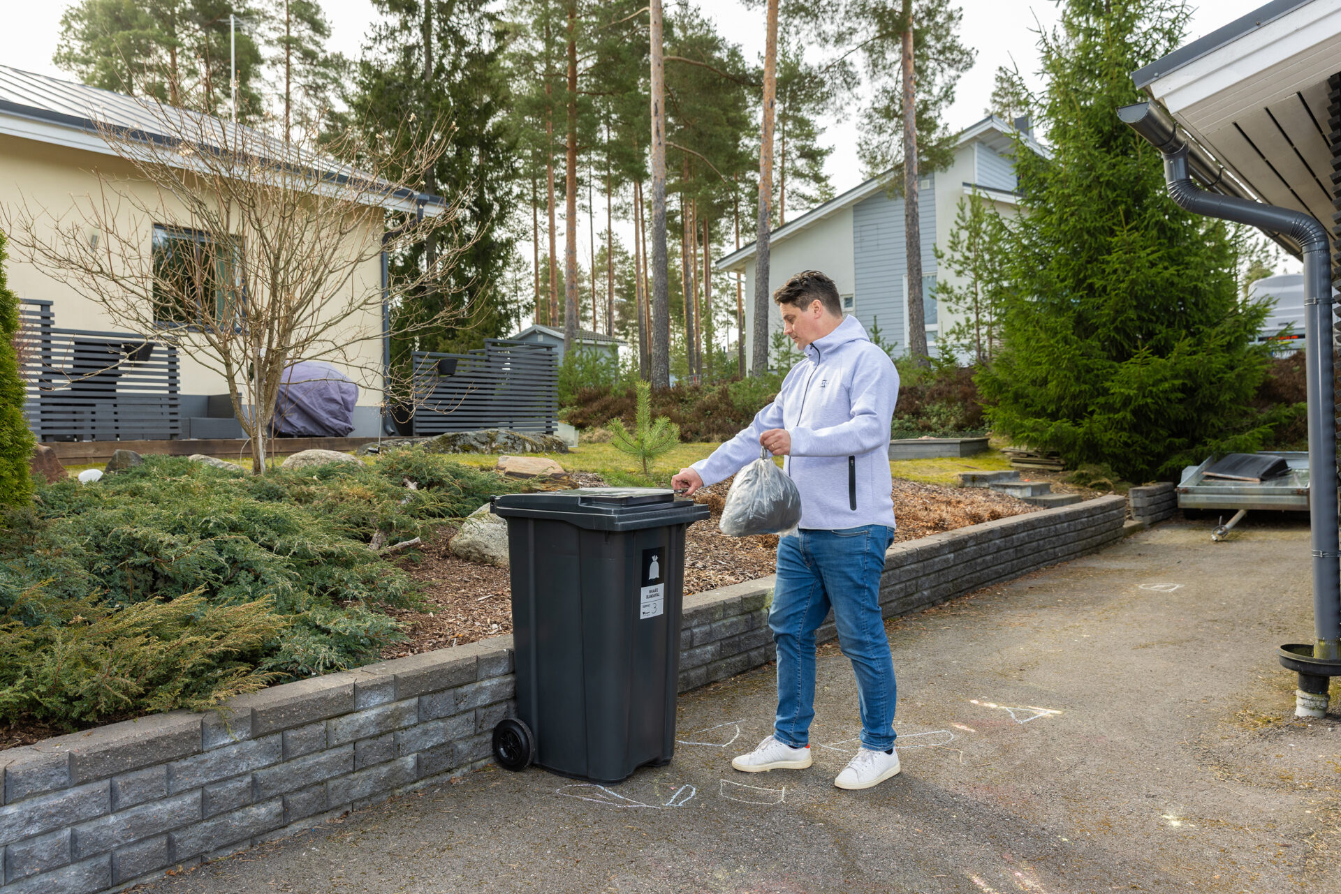Mies vie roskapussia jäteastiaan omakotialueella