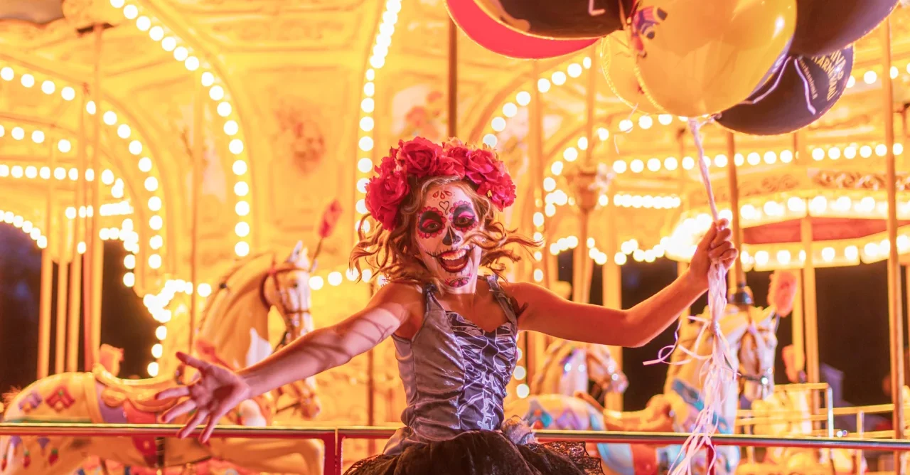 Dia los muertos-tyyliin maskeerattu tyttö valaistussa karusellissa.